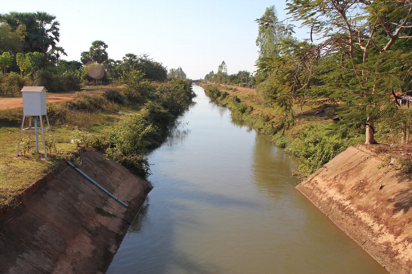 Irrigation canal in Cambodia with a remote water-level monitoring enclosure beside the canal
